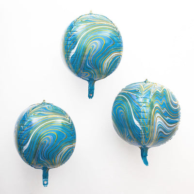 Marbled blue and gold balloons floating against a white background