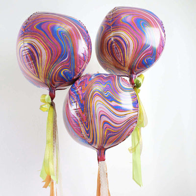 Colorful swirl patterned balloons tied with ribbons against a white backdrop