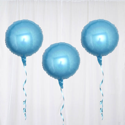 Three blue helium balloons with ribbons floating against a white backdrop