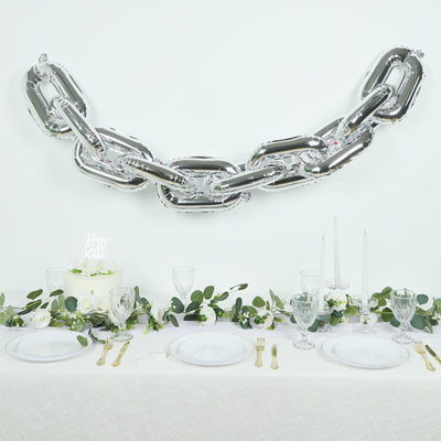 Silver chain balloon decoration over elegant dining table setup.
