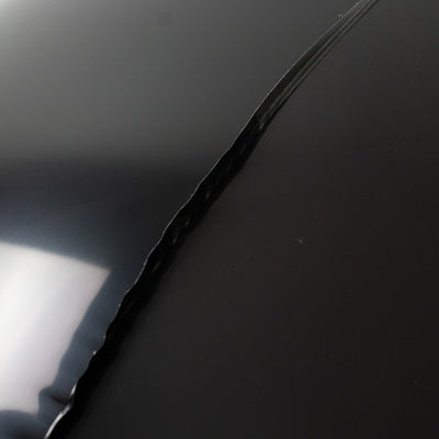 Black shiny surface with a visible crack detail.