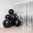 Black balloons clustered in a modern interior with silver foil backdrop.