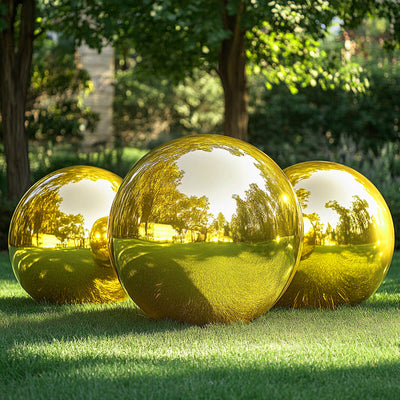 Three reflective gold garden spheres on green grass.