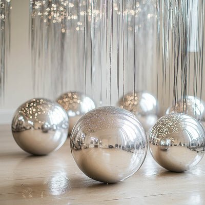 Shiny silver decorative spheres with hanging strands in a bright setting.