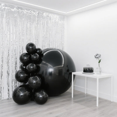 Black balloons and a cake on a table in a festive setting.