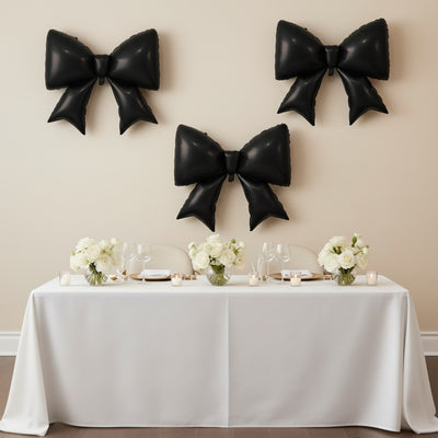 Elegant black balloon bows on a wall above a beautifully set dining table.