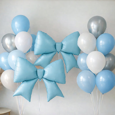 Blue and silver balloons with large bows on a plain backdrop.