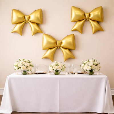 Elegant table setting with gold balloons and floral arrangements for a celebration.