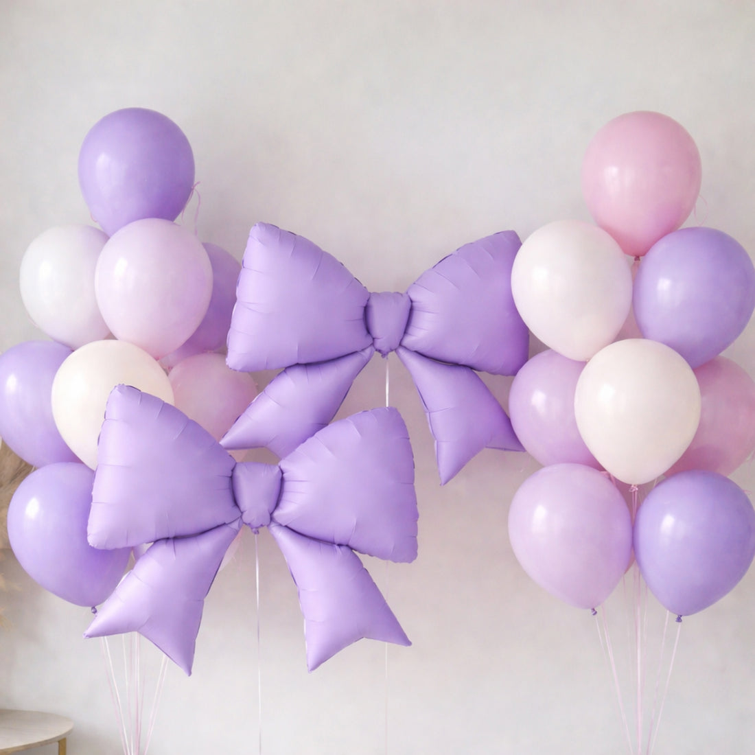 Purple and pink balloons with large bows for festive decor.