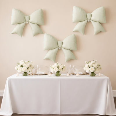Table set for a celebration with floral arrangements and decorative bows on the wall.