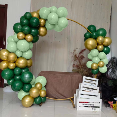 Green and gold balloon arch decor with wooden boxes in a festive setting.