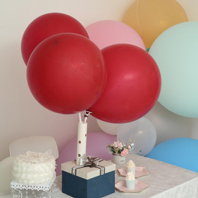 Red balloons with a gift box and cake on a table at a celebration scene.