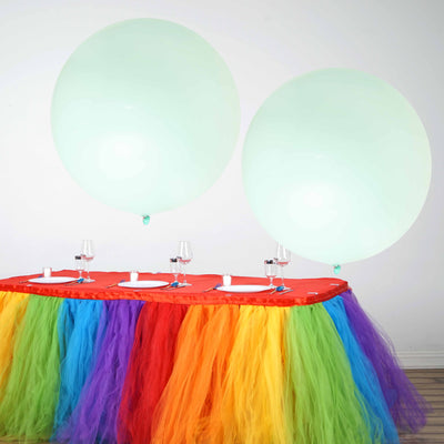 Colorful party table with oversized balloons and vibrant tulle skirt.
