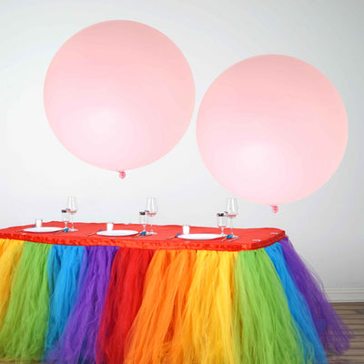 Colorful party table with pink balloons and vibrant tulle decorations.