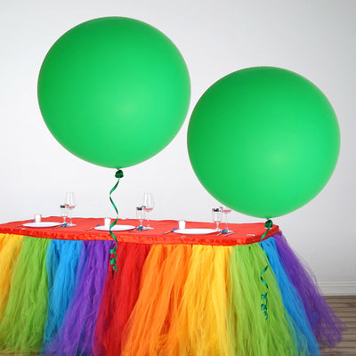 Colorful party table with large green balloons and vibrant tulle skirt.