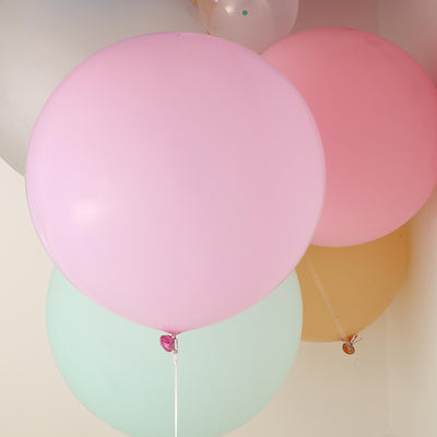 Colorful pastel balloons in various sizes against a plain wall.