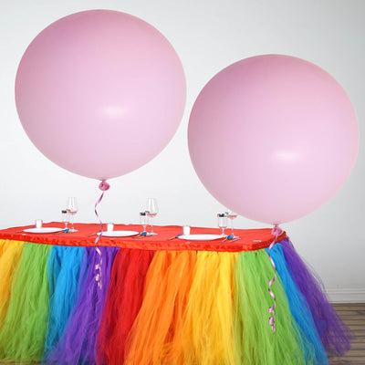 Colorful party table with pink balloons and vibrant tulle decorations.