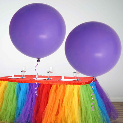 Purple balloons on a colorful table with tulle skirt for festive celebration.