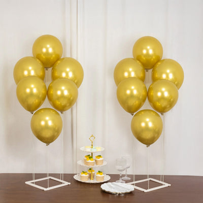 Gold balloons and a dessert stand with cupcakes on a wooden table.