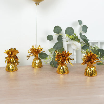 Gold party poppers with shiny foil decorations on a wooden table.