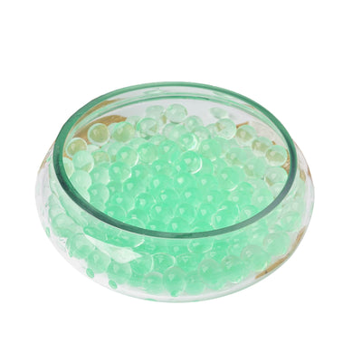 Green decorative water beads in a clear glass bowl.
