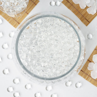 Clear decorative beads in a glass bowl on a white background.