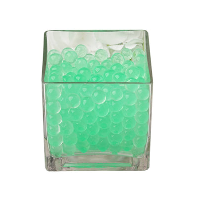 Green decorative water beads in a clear glass container.