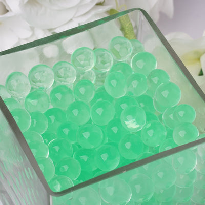 Green gel beads in a clear glass container.