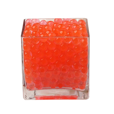 Orange decorative beads in a clear glass container.