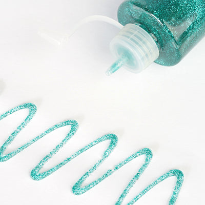 Teal glitter glue in a squeeze bottle with a swirl of glitter on white background