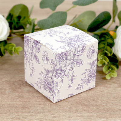 Floral patterned gift box on a wooden surface surrounded by greenery.