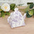Decorative floral teapot on a wooden surface with greenery
