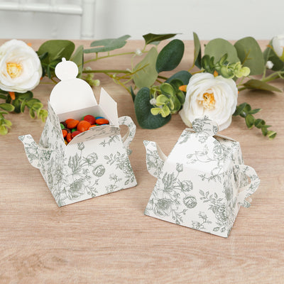 Floral tea party favor boxes with candies inside on a wooden table.