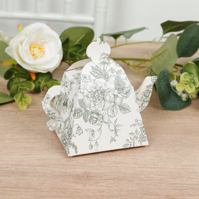 Floral-patterned tea kettle on a wooden surface with greenery.