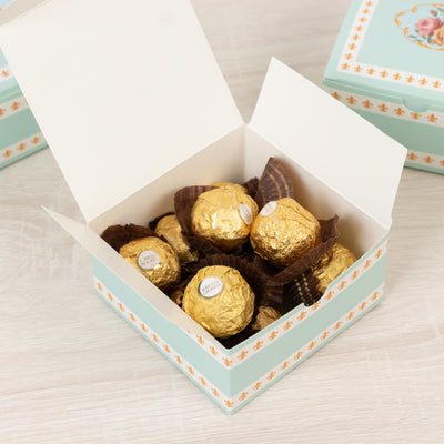 Box of golden chocolate truffles with a decorative lid.