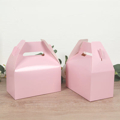 Two pink gift boxes on a wooden surface.