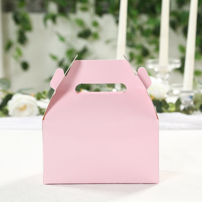 Pink gift box with handle on a table with blurred floral background.