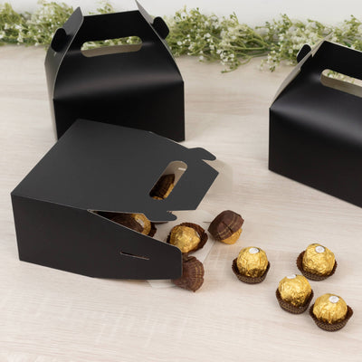 Black takeout boxes with chocolate truffles spilling out on a wooden table.