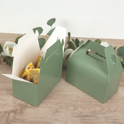 Green takeaway boxes with snacks, set against a wooden surface.