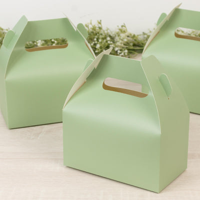 Green takeout boxes with handles on a light wooden surface.