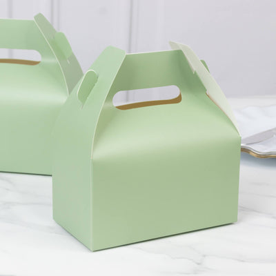 Green paper gift box with handle on a marble surface.