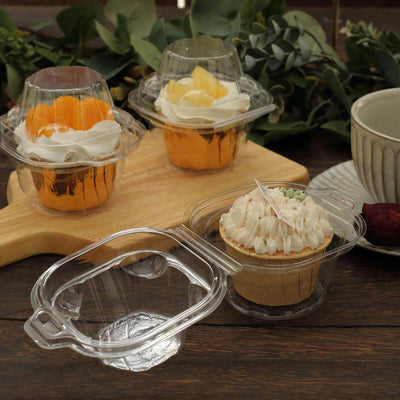 Clear dessert containers with cupcakes and fruit parfaits on a wooden table.