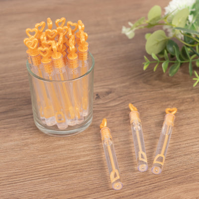 Orange heart-shaped drink stirrers in a glass jar on a wooden surface.
