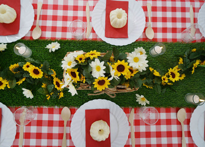 Table setting with flowers and dessert on a red checkered tablecloth.