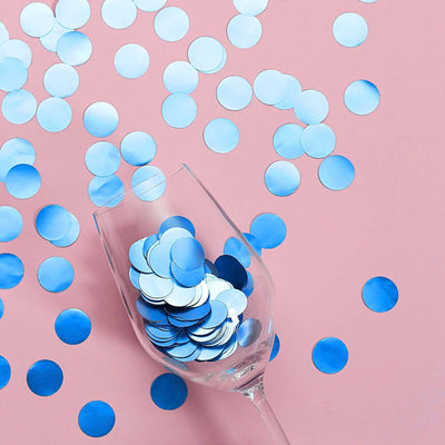 Blue confetti circles scattered around a glass on a pink background.