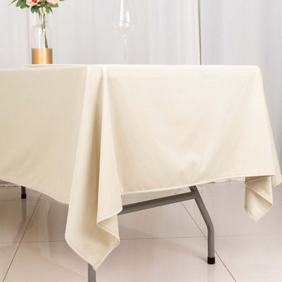 Beige tablecloth draped elegantly over a table with a glass and floral centerpiece.