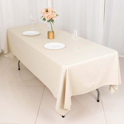 Beige tablecloth draped over a table set with plates and a floral centerpiece.