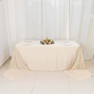 Elegant banquet table with floral centerpiece and plates, draped in cream fabric.