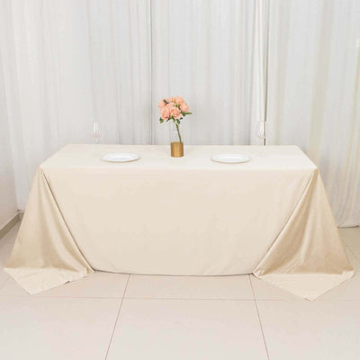 Elegant beige tablecloth draped over a table with floral centerpiece and plates.
