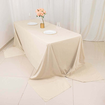 Beige tablecloth draped over a table with floral centerpiece and tableware.